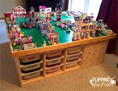 a table with many legos on it and lots of toys in bins underneath