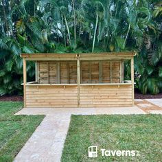 a wooden bar in the middle of a grassy area with palm trees behind it and a stone walkway leading up to it