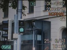 a traffic light sitting on the side of a road next to a tall white building