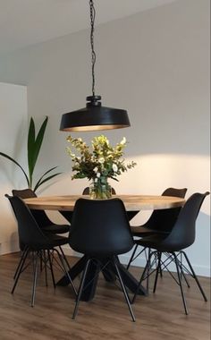 a dining room table with black chairs and a potted plant