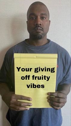 a man holding a yellow piece of paper with the words your giving off fruity vibes