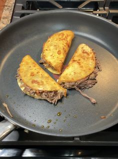 two pieces of meat and cheese in a frying pan on top of the stove