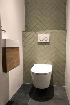 a white toilet sitting inside of a bathroom next to a wall mounted urinals