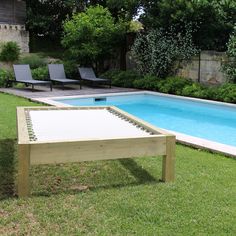 an empty pool in the middle of a lawn with lounge chairs and tables around it