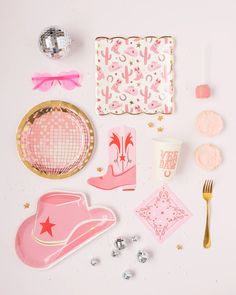 pink and gold party supplies laid out on a white surface