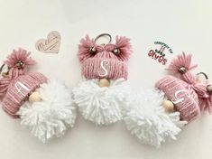 three pink and white knitted angel keychains with monogrammed names on them