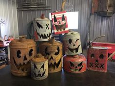 several painted pumpkins are sitting on top of jars in a room with metal walls