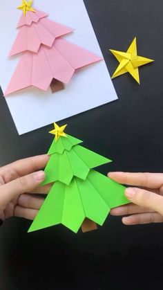 two hands holding origami christmas trees