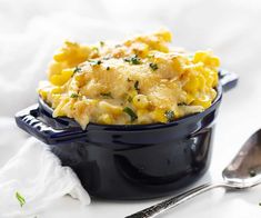 a blue bowl filled with macaroni and cheese on top of a white table