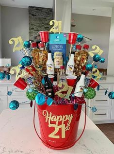 happy 21st birthday gift in a bucket on a counter top with blue and gold decorations