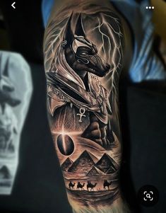 a man with a tattoo on his arm that has an egyptian god and pyramids