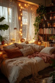 an unmade bed with lots of pillows and blankets on top of it in front of a window