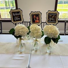 three vases filled with white flowers on top of a table