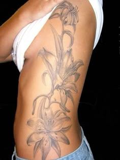 a woman's lower back tattoo with lilies on her ribs and bottom half