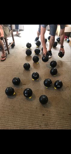 a group of people standing around black balls on the floor