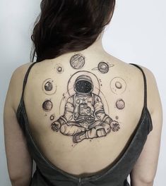 an astronaut tattoo on the back of a woman's upper arm and shoulder, with planets around her