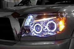 the front end of a silver truck with its lights on