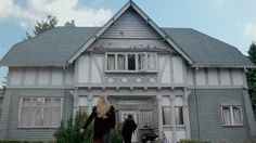 two people are walking in front of a house