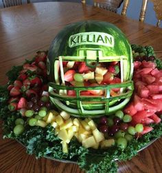 a watermelon helmet made out of fruit on top of a wooden table with other fruits and vegetables