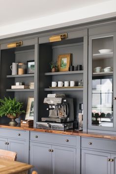 a kitchen with gray cabinets and wooden counter tops, coffee maker on the far wall