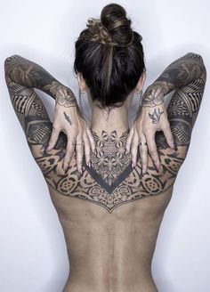 the back of a woman with tattoos on her body and hands behind her head,