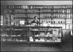 an old black and white photo of a man behind the counter in a liquor store