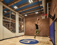 a man jumping up into the air to dunk a basketball in an indoor gym