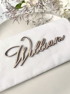 a napkin with the word william on it next to some flowers and a glass vase