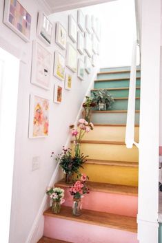 some flowers are sitting on the stairs in front of pictures and framed art hanging on the wall