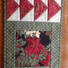 a quilted wall hanging with red flowers and green leaves on the bottom, along with white polka dots