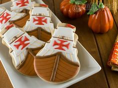 decorated cookies in the shape of boats are on a white plate next to pumpkins