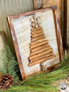 a christmas tree made out of cinnamon sticks is displayed in front of an old frame