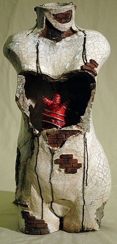 a sculpture made out of broken pieces of paper with a red light in the middle