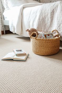 an open book on the floor next to a basket with books in it and a stuffed animal