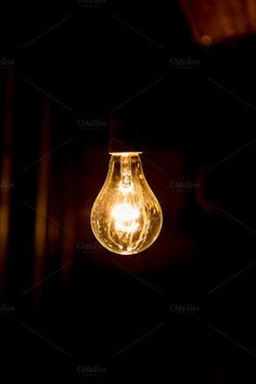 a light bulb hanging from the ceiling in a dark room with no one around it