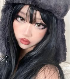 a woman with long black hair wearing a fur hat