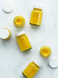 three jars filled with honey sitting on top of a white counter next to two spoons