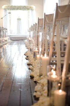 the aisle is lined with white flowers and candles