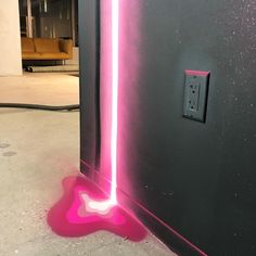 a pink light is shining on the wall next to a black and gray wall with a heart shaped neon strip