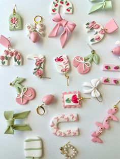 many different types of brooches are arranged on a white surface with pink and green accents