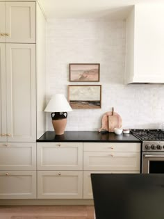 a kitchen with white cabinets and black counter tops is pictured in this image, there are two lamps on the island