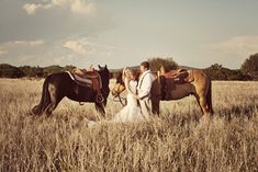 a bride and groom are standing with their horses in the middle of an open field