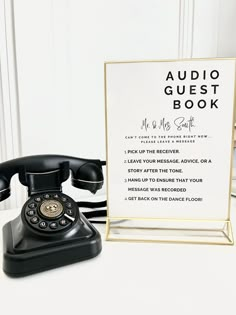 an old - fashioned telephone sits next to a sign that says audio guest book and the phone has been placed in front of it