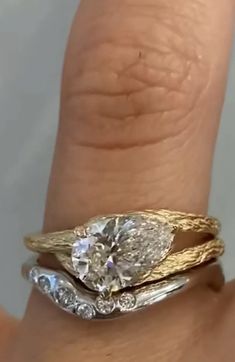 a woman's hand with two gold rings on it and a diamond in the middle