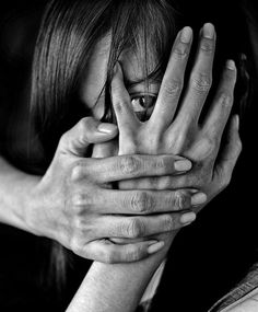 black and white photograph of two people covering their faces with hands, one holding the other's head