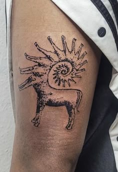 a tattoo on the arm of a person with a cow and sun in the background