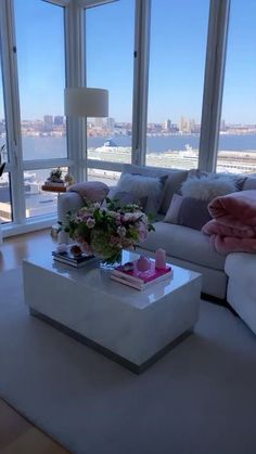 a living room filled with furniture and large windows overlooking the cityscape in the distance