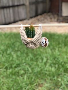 a small stuffed animal hanging from the side of a green grass covered yard next to a wooden fence