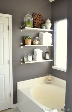 a white bath tub sitting next to a bathroom sink under a window with shelves above it