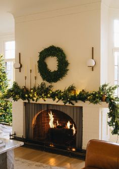 a living room decorated for christmas with wreaths and lights on the fireplace mantel